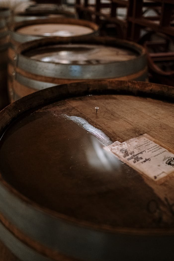 Close-up of oak barrels in a dimly lit winery for fermentation and aging processes.